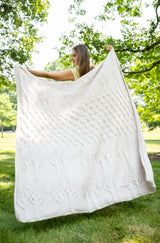 Woman holding knit tree of life blanket made with Wool-Ease yarn thumbnail