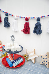 red white and blue yarn and bead garland hung over a patriotic table display thumbnail
