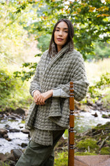 person wearing a textured green waffle-stitch knit blanket wrap outdoors near a stream thumbnail