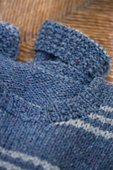 close-up of a two-tone blue striped knit pullover with ribbed and stockinette sections against a wooden background thumbnail