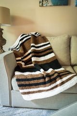 black, brown, and white striped blanket draped over a couch. thumbnail