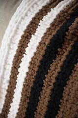 close up of black, brown, and white striped blanket draped over a couch. thumbnail