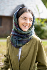 person wearing a multicolored cowl and olive jacket outdoors thumbnail