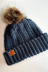 flat lay of blue hat with fur pom pom thumbnail