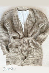 flat lay of a beige crochet cardigan with a tie belt and pockets over a white shirt thumbnail