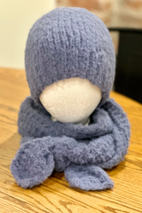 blue knitted wrap scarf and matching beanie displayed on a white foam mannequin head resting on a wooden surface thumbnail