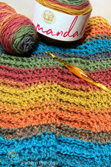 close-up of colorful crocheted blanket with lion brand mandala yarn cake and crochet hook thumbnail