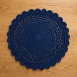 navy blue crocheted round placemat with openwork lattice and scalloped edge laid flat on a light wood surface thumbnail