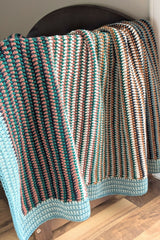 crochet baby blanket draped over a wooden chair thumbnail