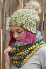 woman wearing a teal alpine stitch crochet beanie with a faux fur pom pom and matching cowl outdoors thumbnail
