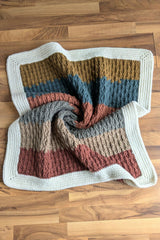 Overhead view of striped crochet blanket with white border thumbnail