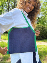 Woman with a crochet tote bag with special shaping, in green and blue on her shoulder. thumbnail
