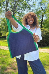 Woman holding out a crochet tote bag with special shaping, in green and blue thumbnail