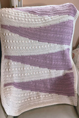 Purple and white baby blanket draped on a chair thumbnail