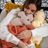 Young women hugging stuffed dog, stuffed dinosaur and stuffed elephant made with Cover Story yarn. thumbnail