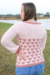 woman wearing a light pink crocheted heart motif sweater outdoors thumbnail