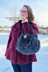 woman holding a dark blue crocheted hobo handbag with a button closure thumbnail