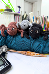 handmade plush yarn spiders with eyes sitting on teal yarn skein thumbnail