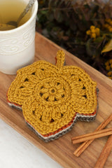 crocheted leaf-shaped coasters in autumn colors on a wooden board next to a cup of tea thumbnail
