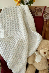 textured crocheted baby blanket draped on a chair with teddy bear thumbnail