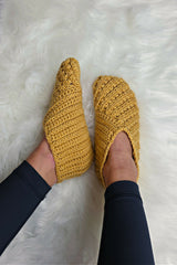 pair of mustard yellow crocheted Willow slippers worn on feet over a fluffy white rug thumbnail