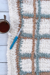 Plaid blanket with a crochet hook and mug thumbnail