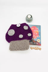 purple toadstool mushroom-shaped crocheted sleeve next to book thumbnail