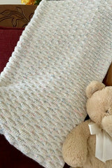 textured crocheted baby blanket draped on a chair with teddy bear thumbnail