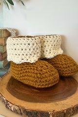 handmade beaver creek crochet booties with brown soles and cream fold down cuffs on a wooden surface thumbnail