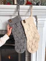 handmade gray and beige crochet Christmas stockings with basketweave texture hanging on a white mantel with a fireplace thumbnail