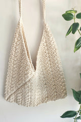 ecru bag hanging on a wall next to a plant thumbnail