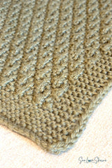 close-up of sage green knitted seersucker blanket edge showing textured stitch pattern and garter stitch corner thumbnail