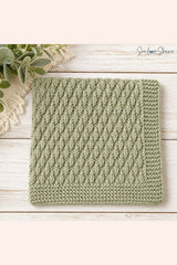 sage green knitted seersucker swatch folded flat on a light wood surface with greenery and macrame trim in the background thumbnail