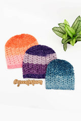 three textured crocheted beanie hats in orange, purple, and blue flat laid with a plant thumbnail