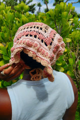 pink and cream yarn hat with floral patterns and textured details worn over the head thumbnail