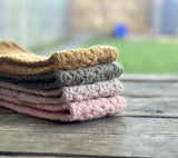 stack of folded star stitch crochet headbands in various neutral and pastel colors on a wooden surface thumbnail