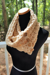 beige crocheted tulip stitch cowl with brown wooden buttons displayed on a black mannequin bust against an outdoor greenery background thumbnail