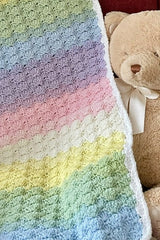 pastel rainbow crocheted baby blanket draped on a chair with teddy bear thumbnail