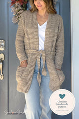 person wearing a beige crochet cardigan jeans and white shirt standing near a blue door thumbnail