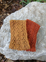 rust orange and mustard yellow crocheted ear warmer headbands stacked on a rock thumbnail