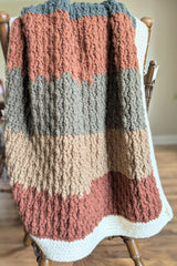 striped crochet blanket with white border draped on the back of a chair thumbnail