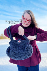 woman holding a dark blue crocheted hobo handbag with a button closure thumbnail