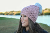 woman wearing a dusty pink crocheted beanie with a fur pom-pom thumbnail