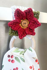 crocheted red poinsettia appliqué with green leaves attached to the wooden ring of a patterned towel holder thumbnail