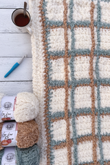 Plaid blanket with yarn skeins, crochet hook, and mug. thumbnail