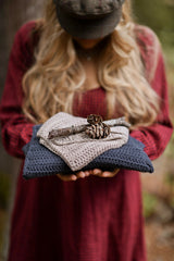Woman holding knit scarf in woods with a stick and pine cone thumbnail
