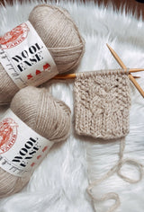 two balls of wool-ease yarn and fingerless gloves on a knitting needle thumbnail