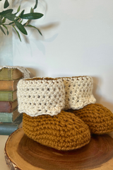 handmade beaver creek crochet booties with brown soles and cream fold down cuffs on a wooden surface thumbnail