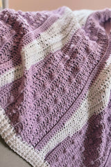 Purple and white baby blanket draped on a chair thumbnail