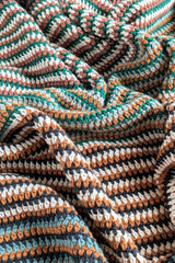 folded crochet blanket with green orange and white stripes thumbnail